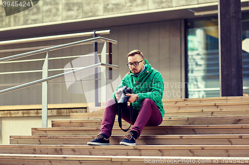 Image of young hipster man with digital camera in city