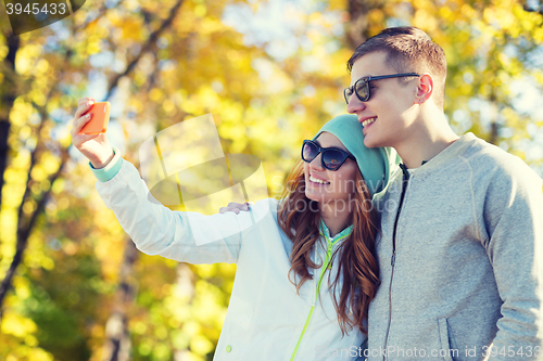 Image of smiling couple with smartphone taking selfie