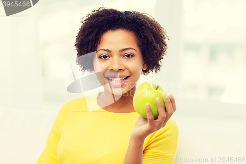 Image of happy african american woman with green apple