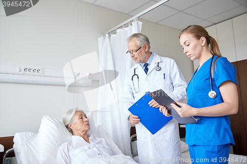 Image of doctor and nurse visiting senior woman at hospital