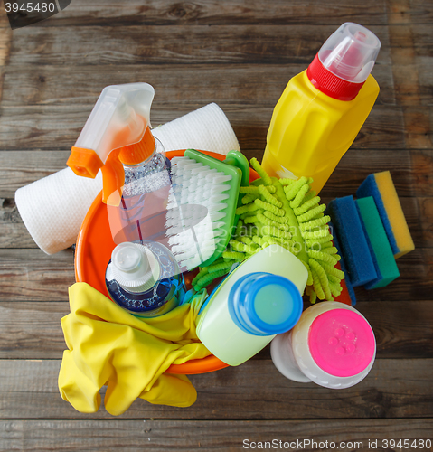 Image of Plastic bucket with cleaning supplies on wood background