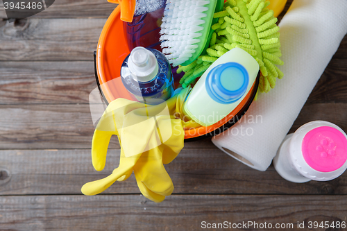 Image of Plastic bucket with cleaning supplies on wood background