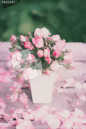 Image of Roses in white vase on a wooden table