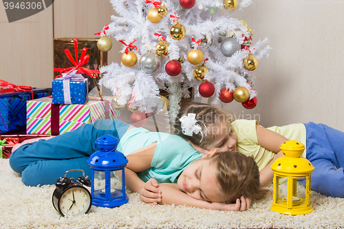 Image of Two girls slept through the whole New Years Eve at the Christmas tree while waiting for the arrival of Santa Claus and gifts