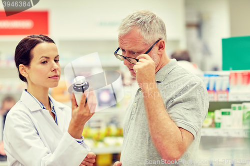 Image of pharmacist showing drug to senior man at pharmacy