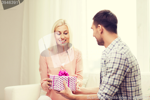 Image of happy man giving woman gift box at home