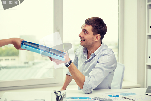 Image of businessman taking papers from secretary in office