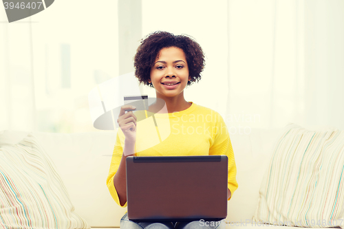 Image of happy african woman with laptop and credit card