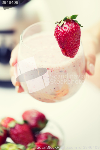 Image of close up of hand holding glass with fruit shake