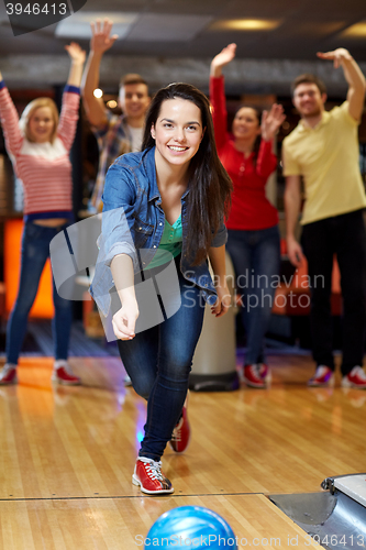 Image of happy young woman throwing ball in bowling club