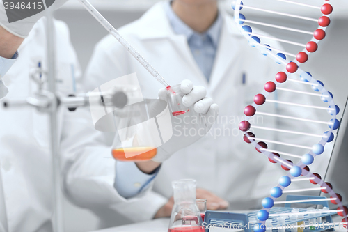 Image of close up of scientists filling test tube in lab