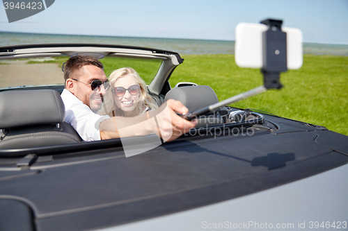 Image of happy couple in car taking selfie with smartphone