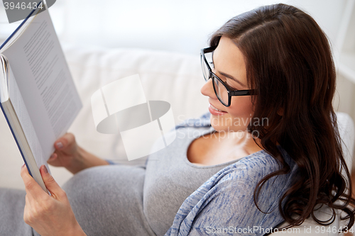 Image of happy pregnant woman reading book at home