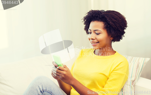 Image of happy african woman with smartphone at home