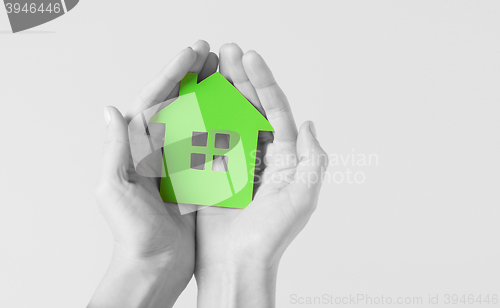 Image of hands holding green paper house