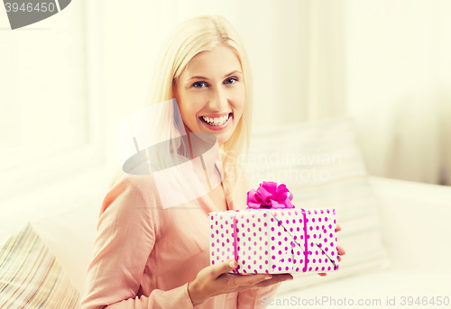 Image of smiling woman with gift box at home