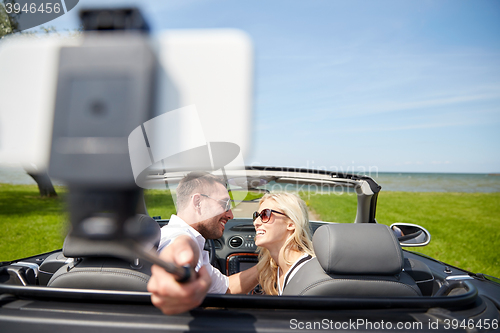 Image of happy couple in car taking selfie with smartphone