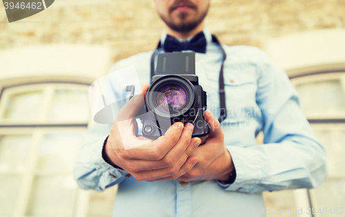 Image of close up of hipster man with film camera in city