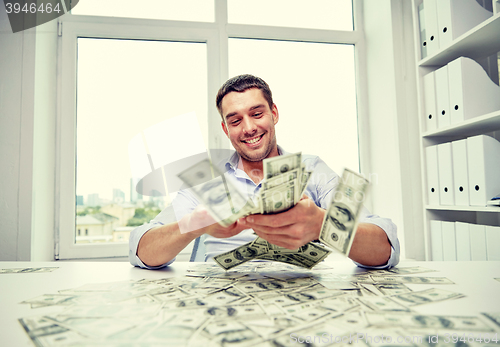 Image of happy businessman with heap of money in office