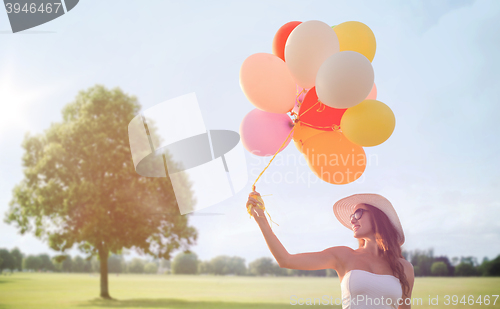 Image of smiling young woman in sunglasses with balloons