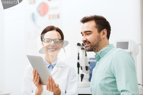 Image of optician with tablet pc and patient at eye clinic