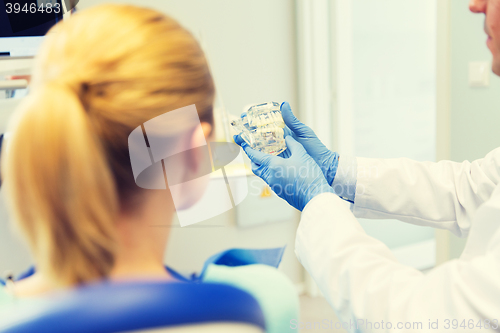 Image of close up of dentist showing teeth model to patient