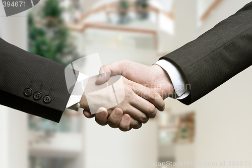 Image of business hand shake and a office in background