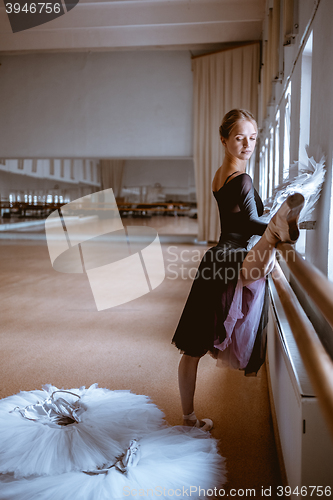 Image of The young modern ballet dancer posing against the room background