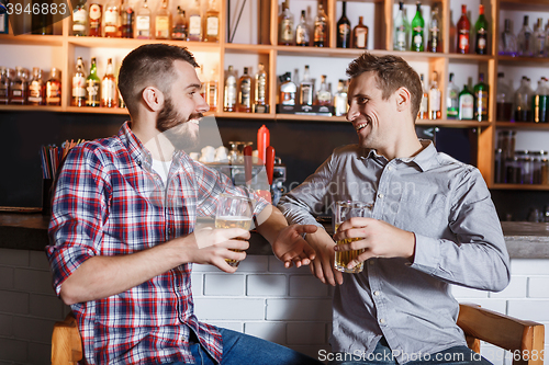 Image of Happy friends drinking beer at counter in pub