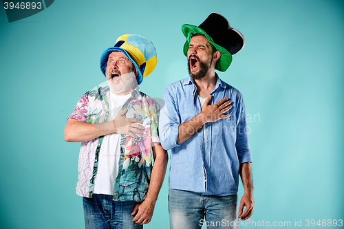 Image of The two football fans singing the national anthem over blue