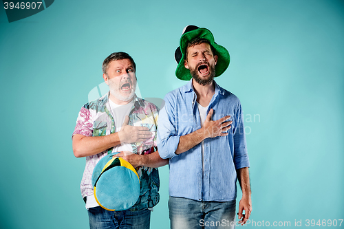 Image of The two football fans singing the national anthem over blue