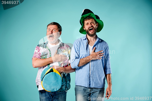 Image of The two football fans singing the national anthem over blue