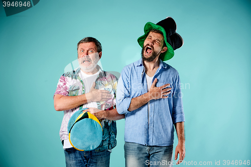 Image of The two football fans singing the national anthem over blue