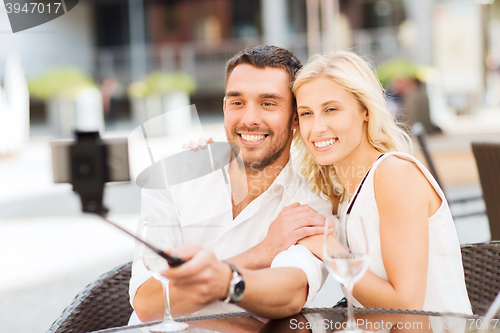 Image of happy couple taking selfie with smartphone at cafe