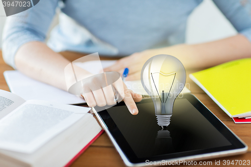 Image of close up of student with light bulb on tablet pc