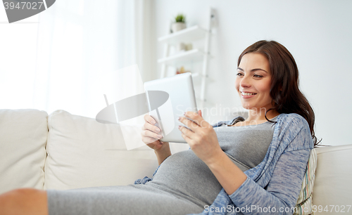 Image of happy pregnant woman with tablet pc at home