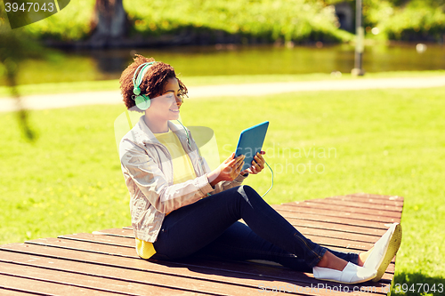 Image of happy african woman with tablet pc and headphones