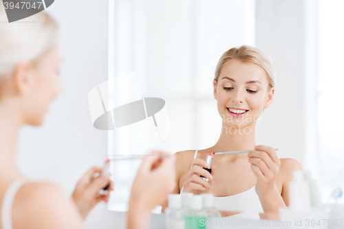 Image of woman with lipstick applying make up at bathroom