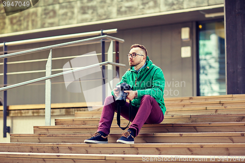 Image of young hipster man with digital camera in city