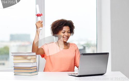 Image of happy african woman with laptop, books and diploma