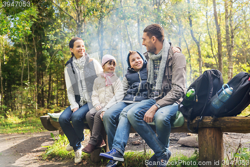 Image of happy family sitting on bench and talking at camp