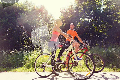 Image of happy couple riding bicycle outdoors