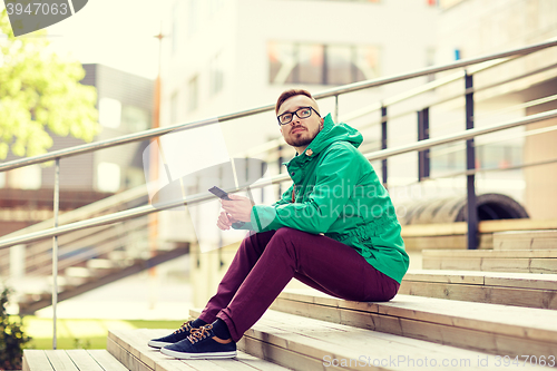 Image of young hipster man with smartphone in city