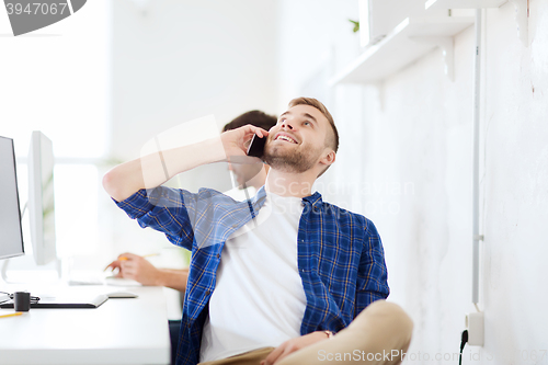 Image of happy creative man calling on cellphone at office