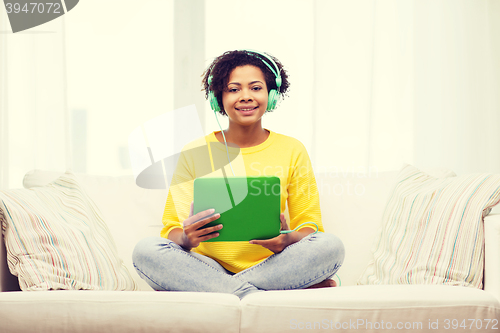 Image of happy african woman with tablet pc and headphones