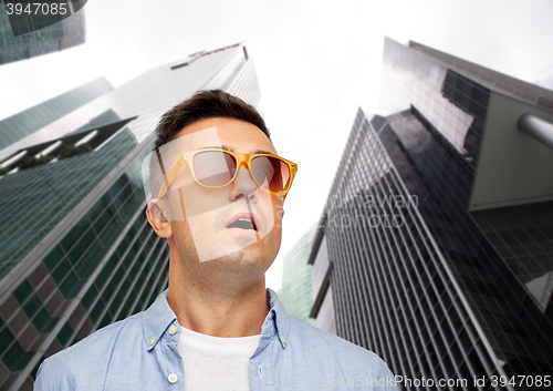 Image of face of scared man in sunglasses over big city