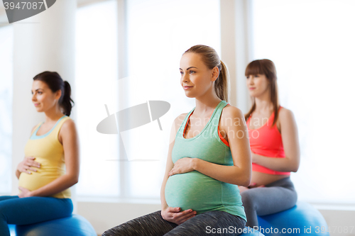 Image of happy pregnant women exercising on fitball in gym