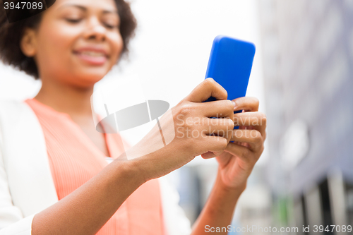 Image of close up of african woman with smartphone in city