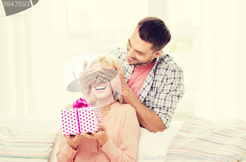 Image of happy man giving woman gift box at home