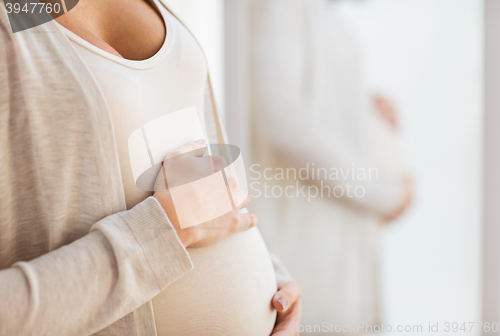 Image of close up of pregnant woman belly at mirror